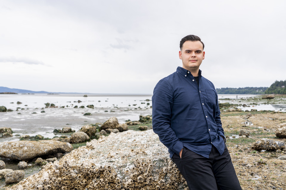 Law student Andrew Ambers walks along the shoreline while smiling.