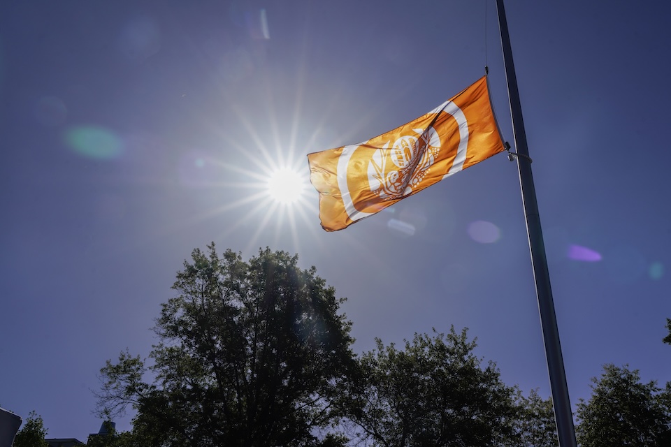 A orange and white flag flies in the wind on a flag pole.