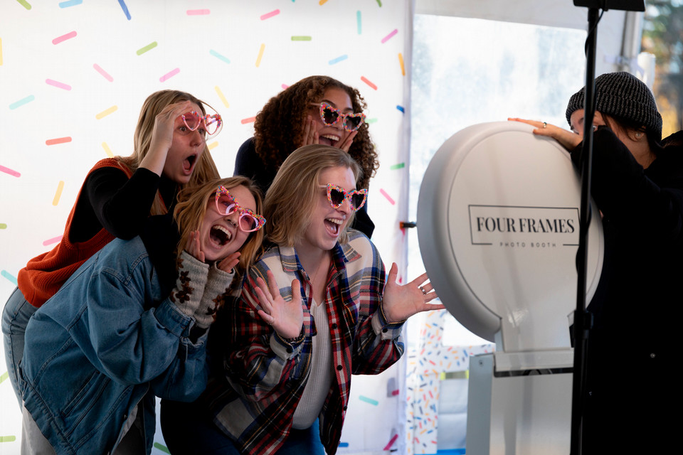 Four students pose in a photo booth wearing glasses.