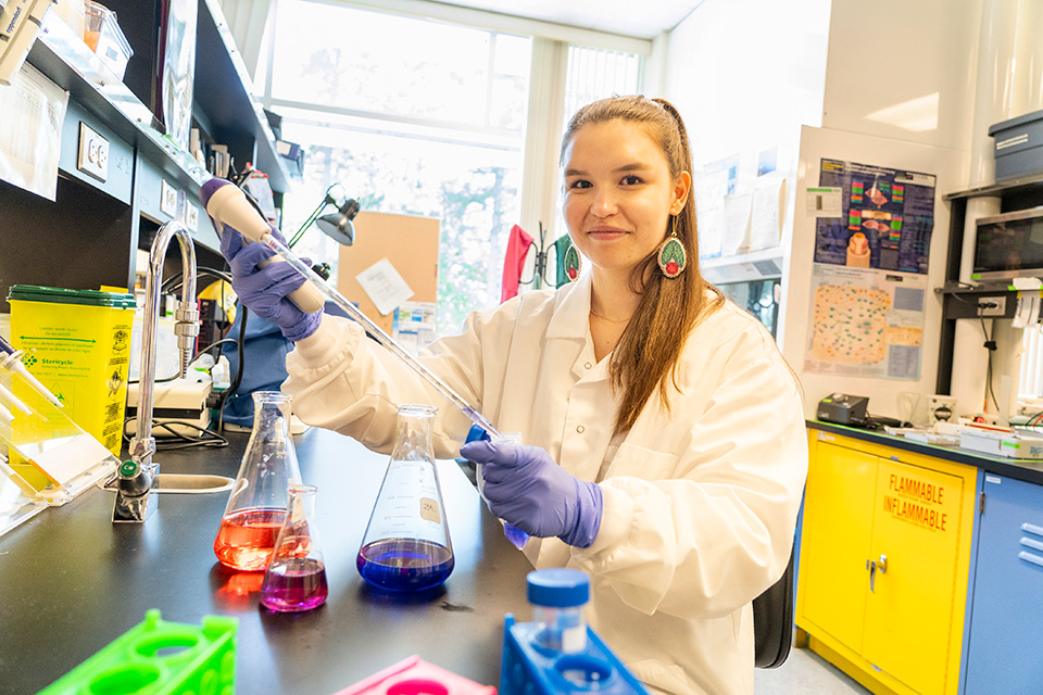 Student working in a lab with colourful instruments, jars and liquids