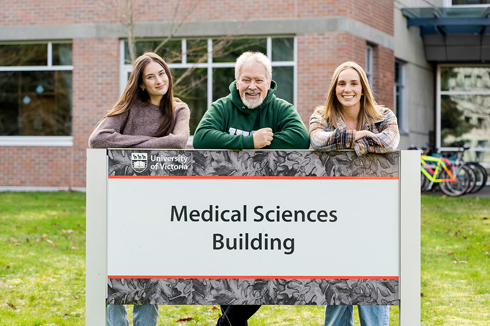 Jamie Morrison, Brian Christie and Taylor Snowden stand in front of the sign for the Medical Sciences Building at UVic.