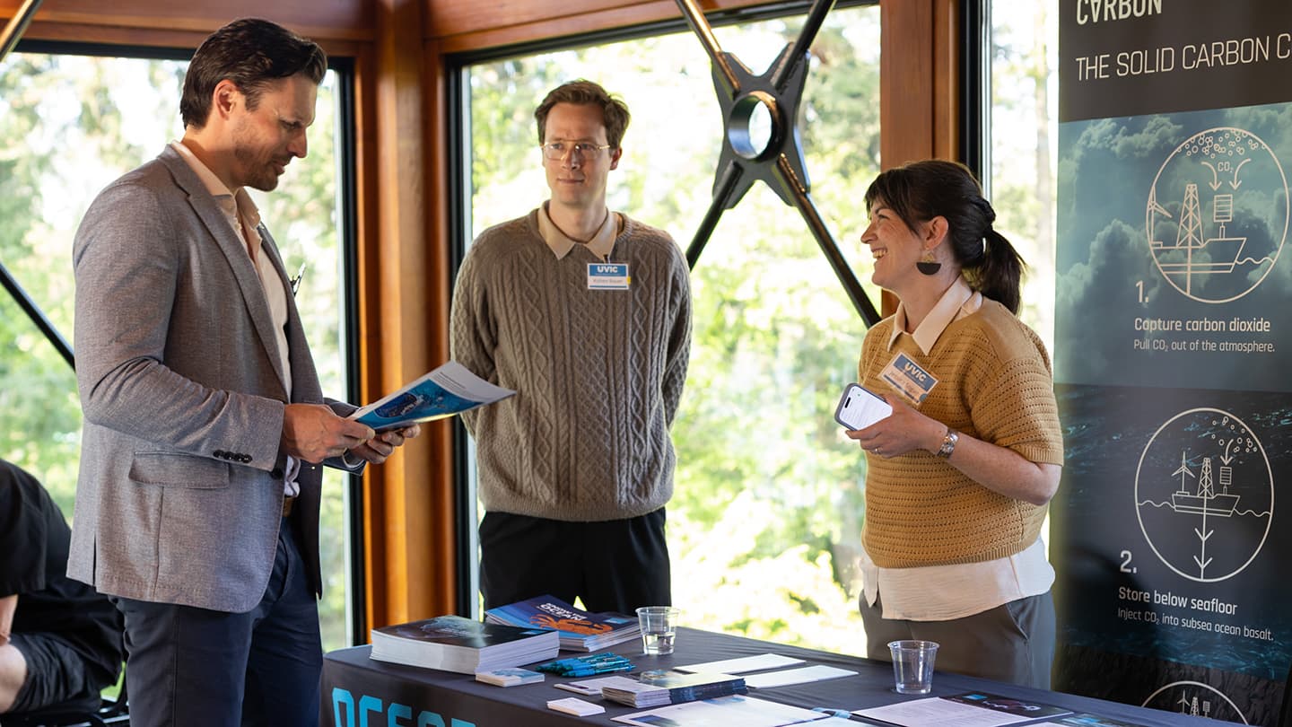 An attendee speaks with two representatives from Ocean Networks Canada.