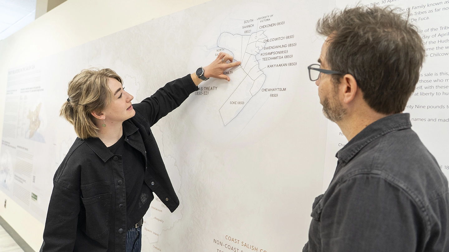 Two people standing in front of a map.