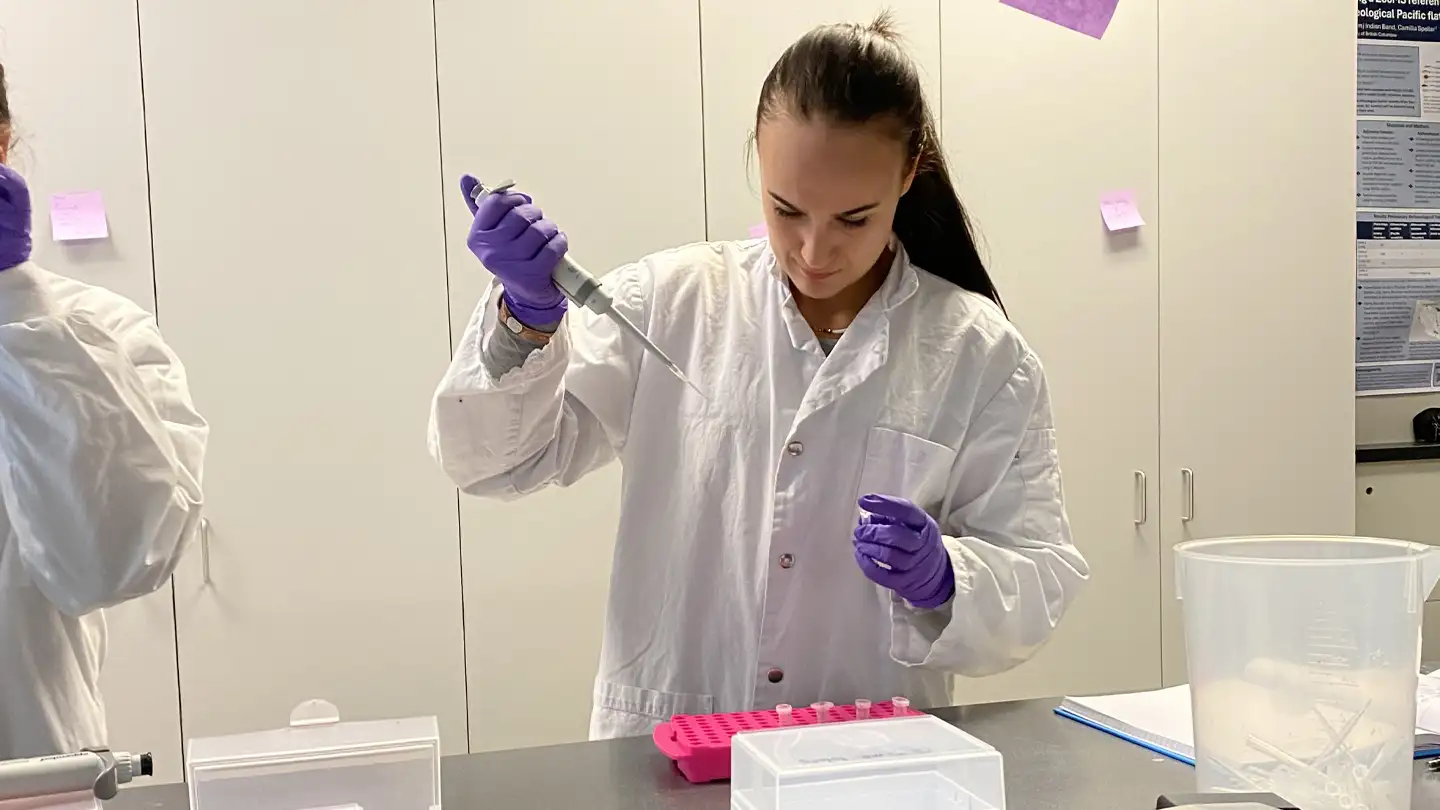 A student wearing a lab coat in a lab.