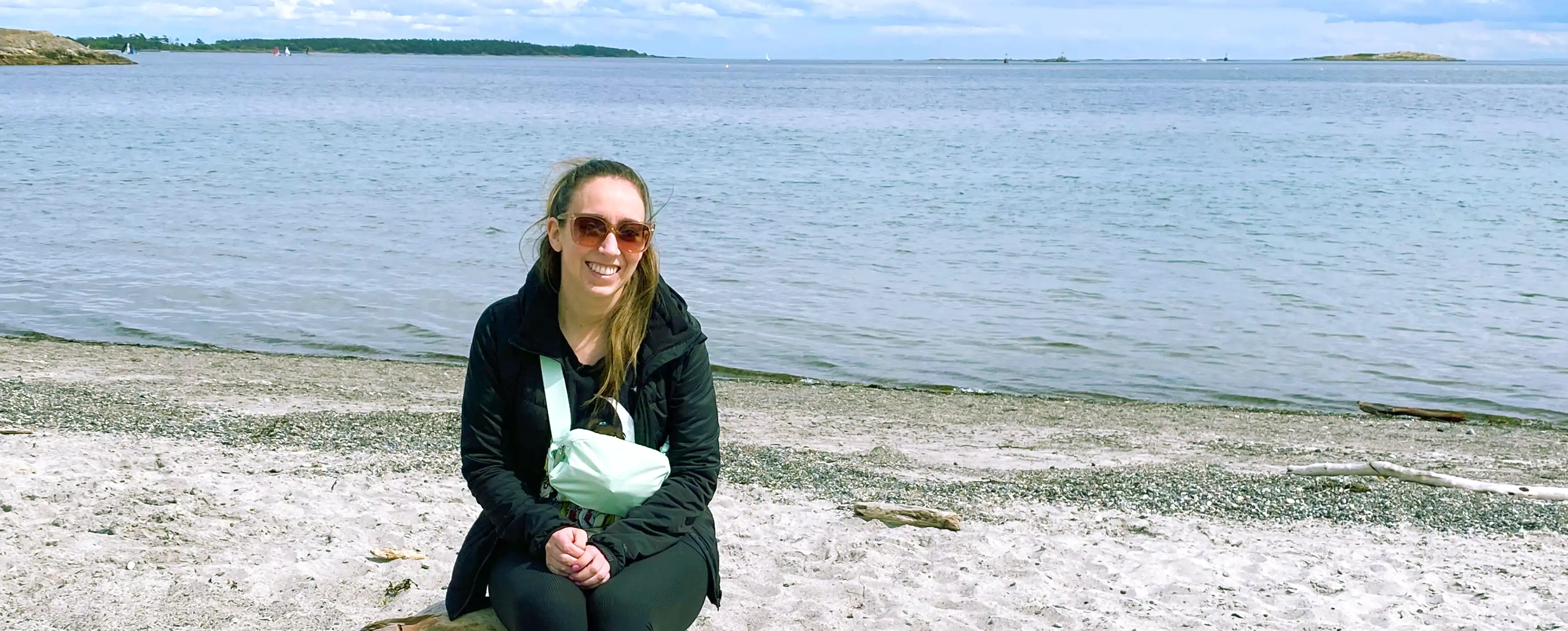 A student sits on the beach in front of the ocean.