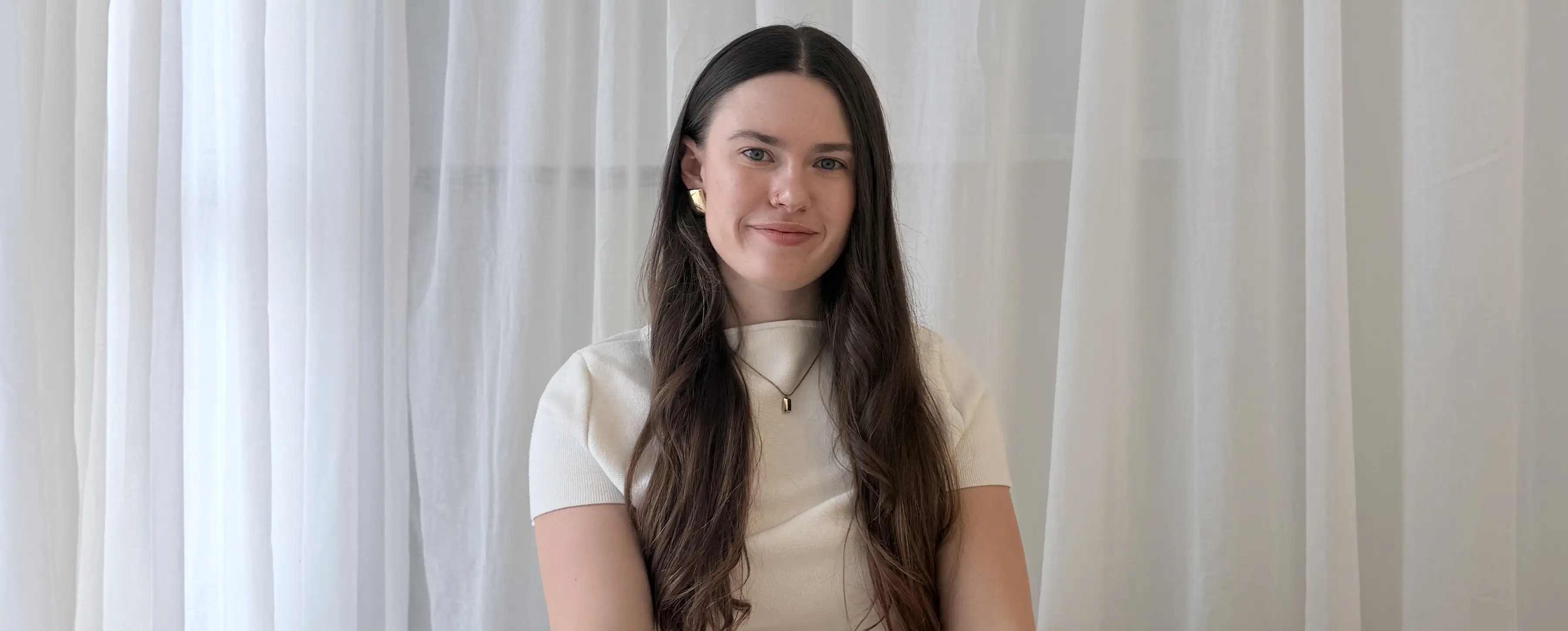 A student poses in front of a white curtain background.