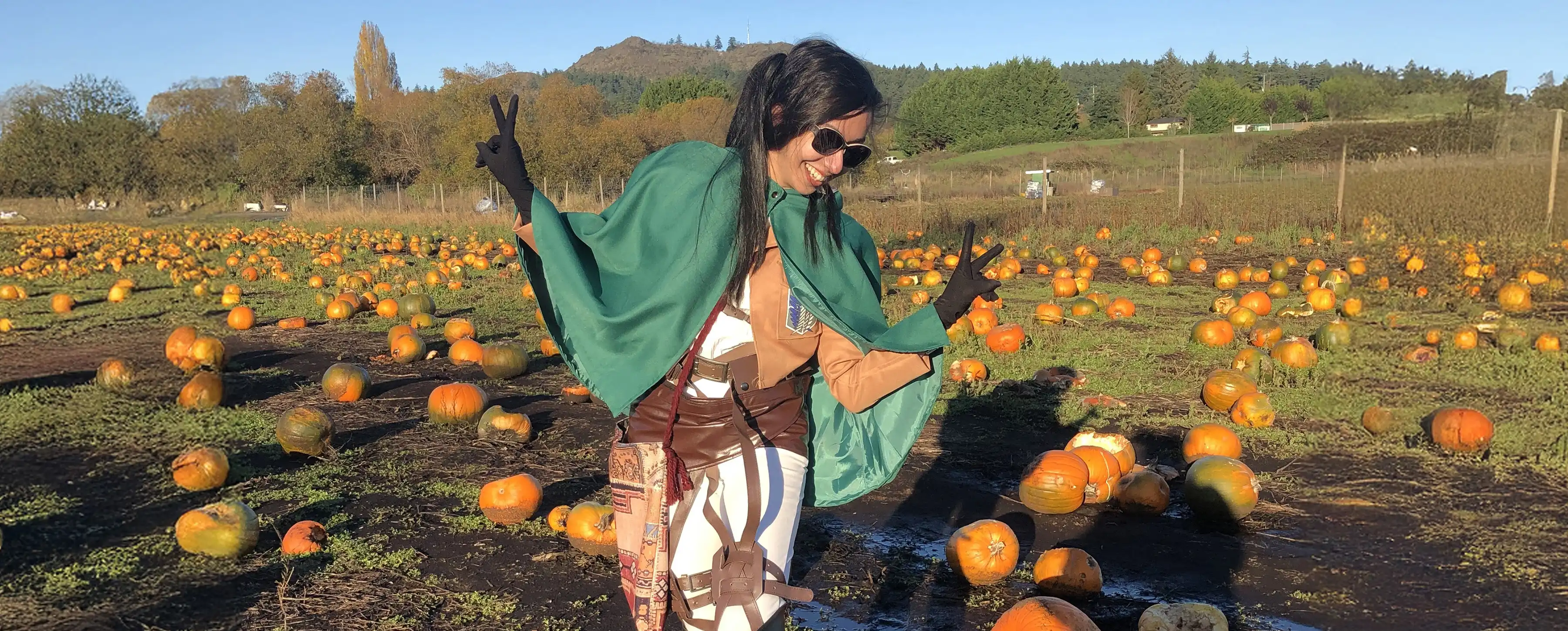 A student gives the peace sign while standing in a pumpkin patch.