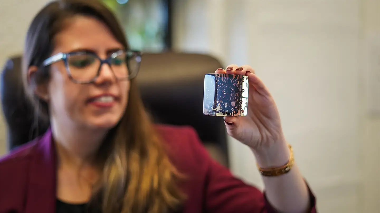 A woman wearing glasses holding up a 3D-printed tissue model.