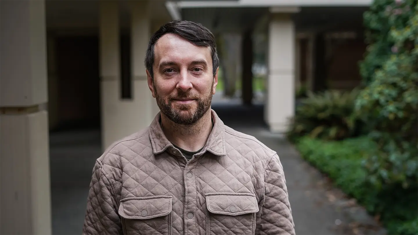 A man with facial hair standing in the atrium of a building.  