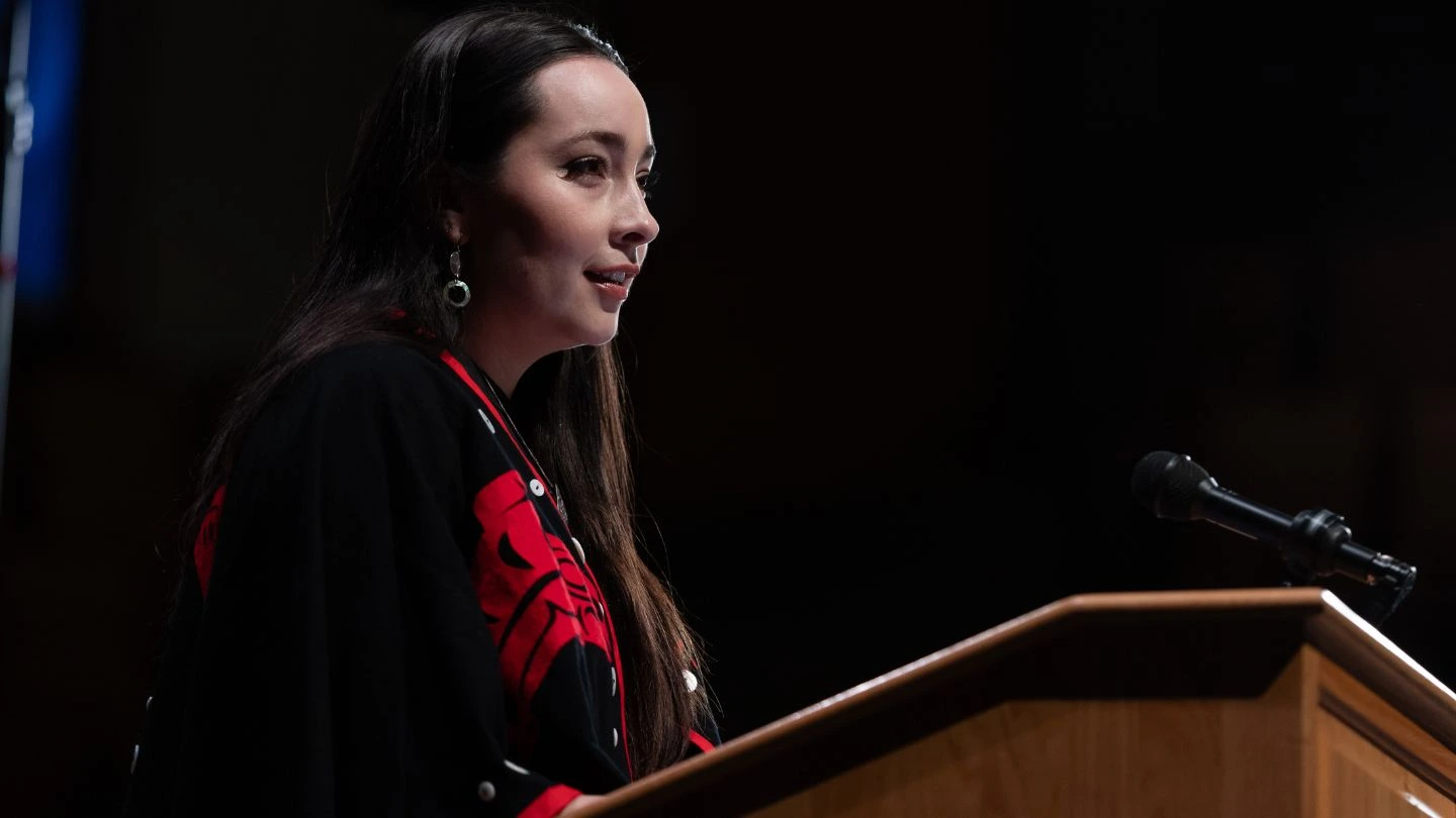 The host of the Conversation of a Lifetime, PICS Indigenous Research and Partnerships Lead Janna Wale, opens the evening. Janna is wearing her regalia, a Gitxsan button blanket in red and black.