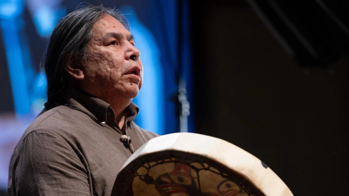 Yuxwelupton Qwal’ qaxala Bradley Dick begins the conversation with a territorial welcome. He plays a drum and sings.