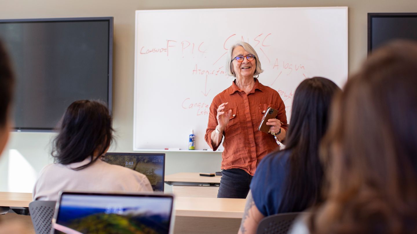 Val Napoleon gestures at the front of a classroom of students.