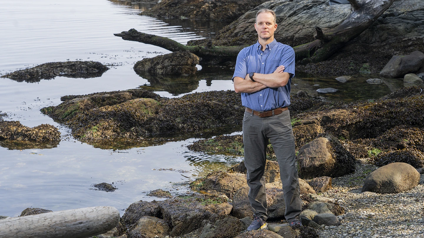 Adrian Marchetti standing on a rocky shore.