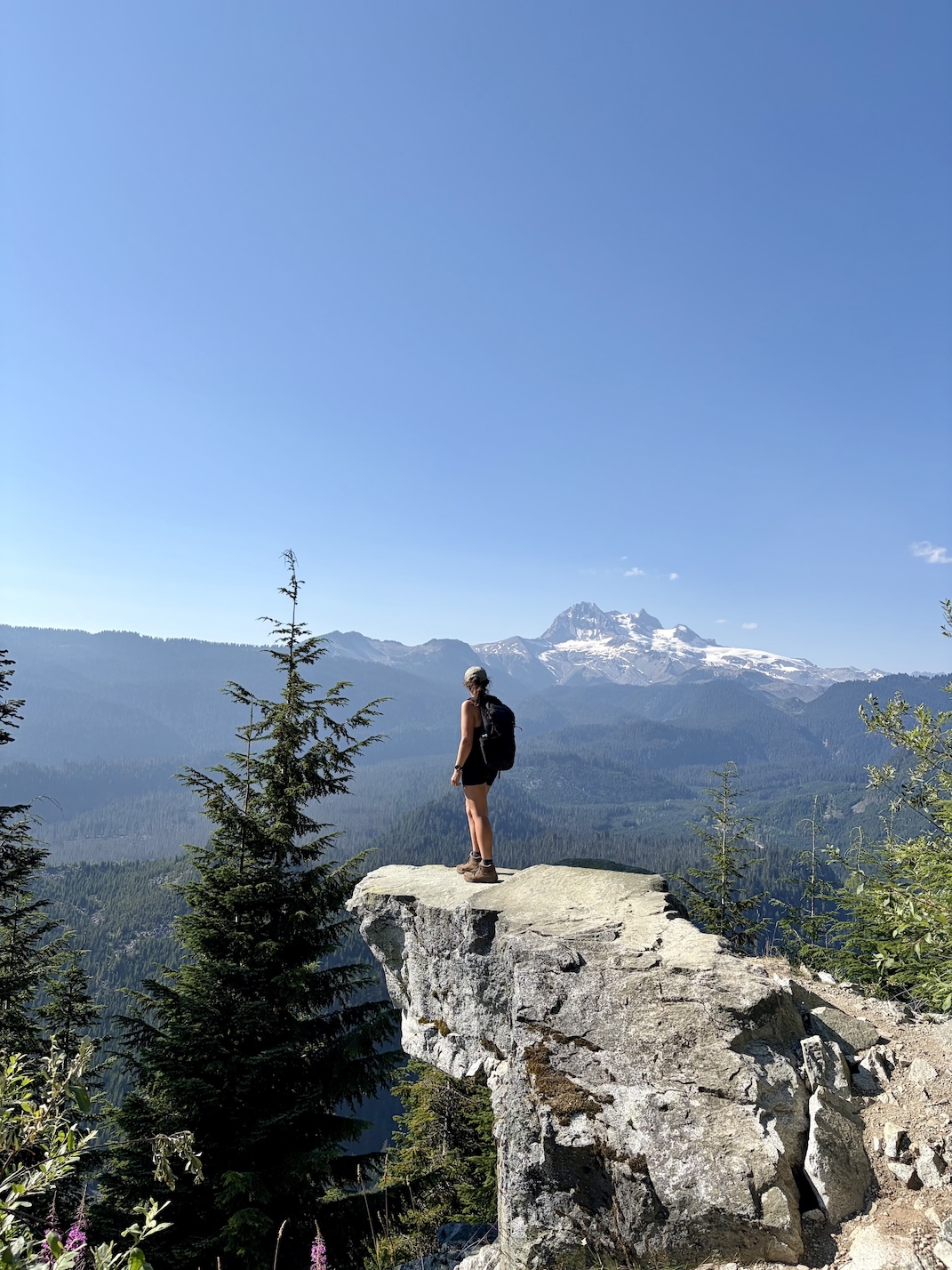 Emma Claydon stands on a cliff while hiking in the mountains.