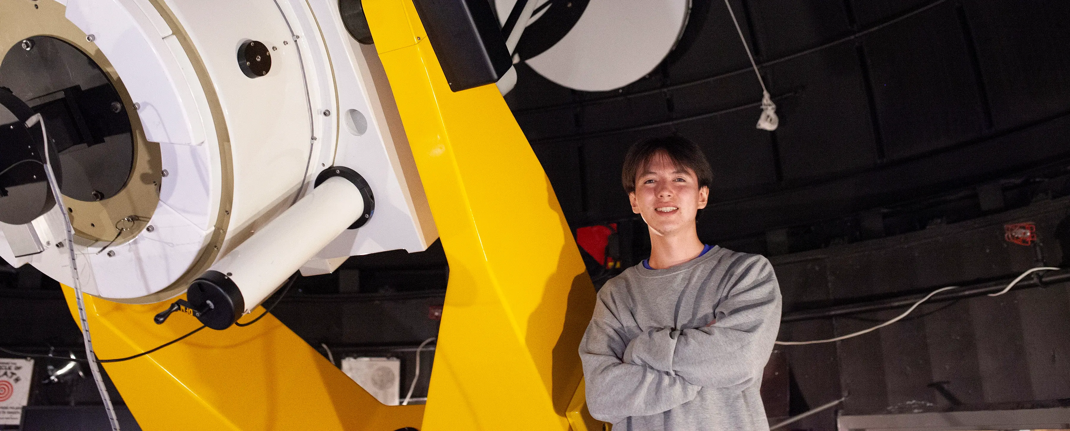 Riley Friesen stands next to UVic’s 0.8m DFM telescope.